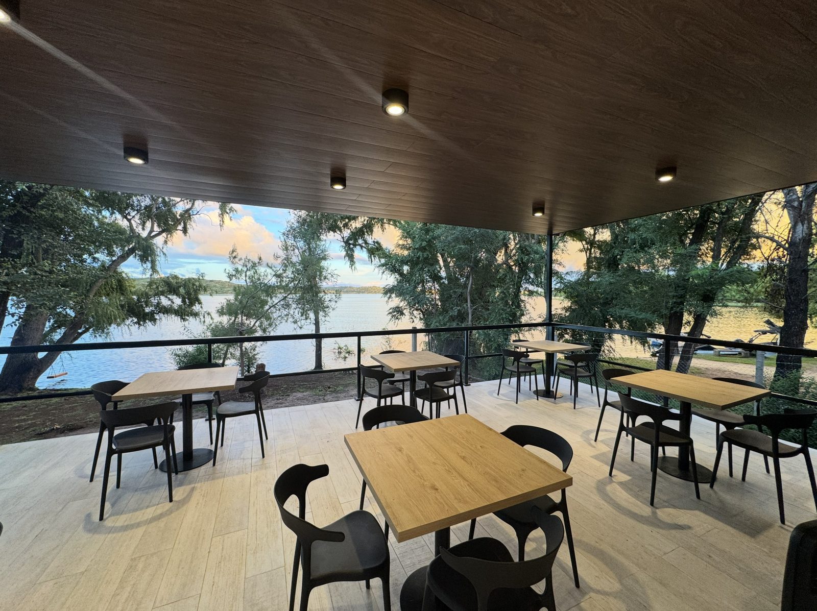 Terrace tables overlooking the lake through the trees at dusk